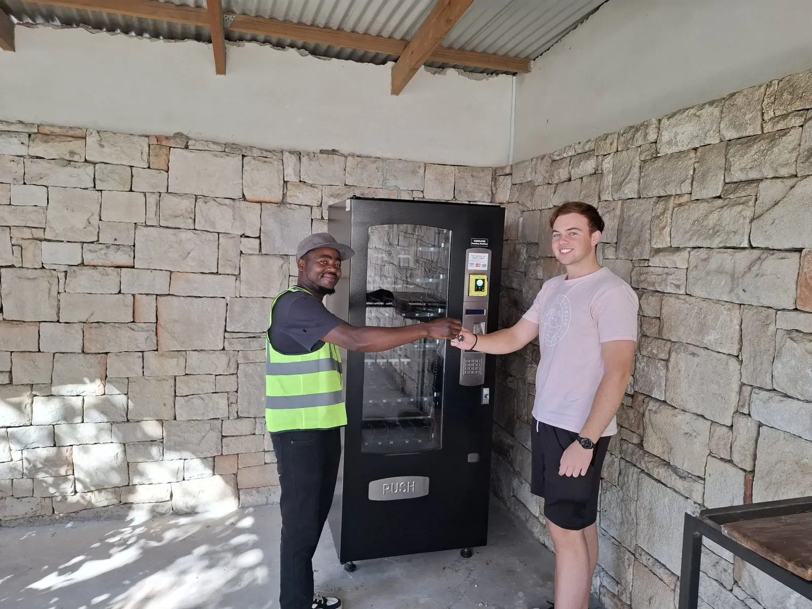 An IVS technician shaking hands with a customer beside a newly delivered vending machine