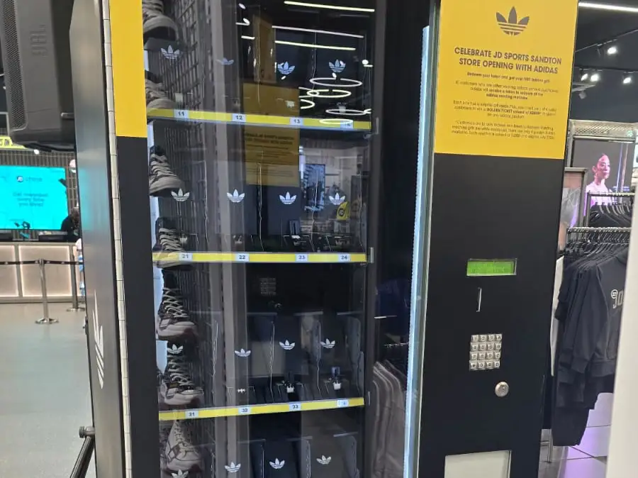 An adidas-branded token-operated gift vending machine at the JD Sports Sandton store opening, stocked with sneakers and gift boxes