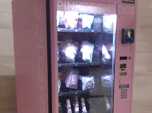 A pink custom-branded cosmetics vending machine stocked with beauty products
