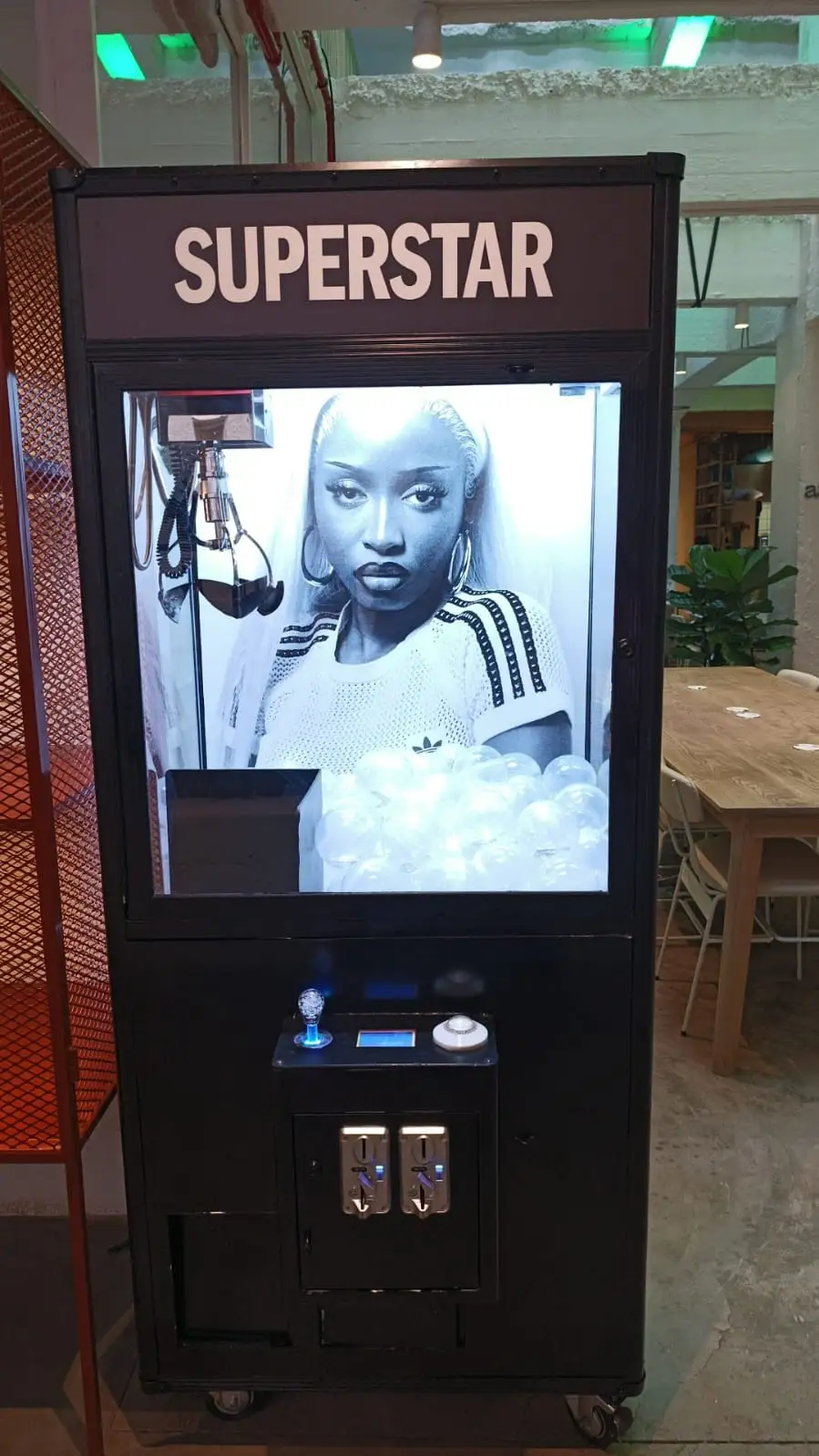 A branded adidas claw machine with a Superstar campaign on its display