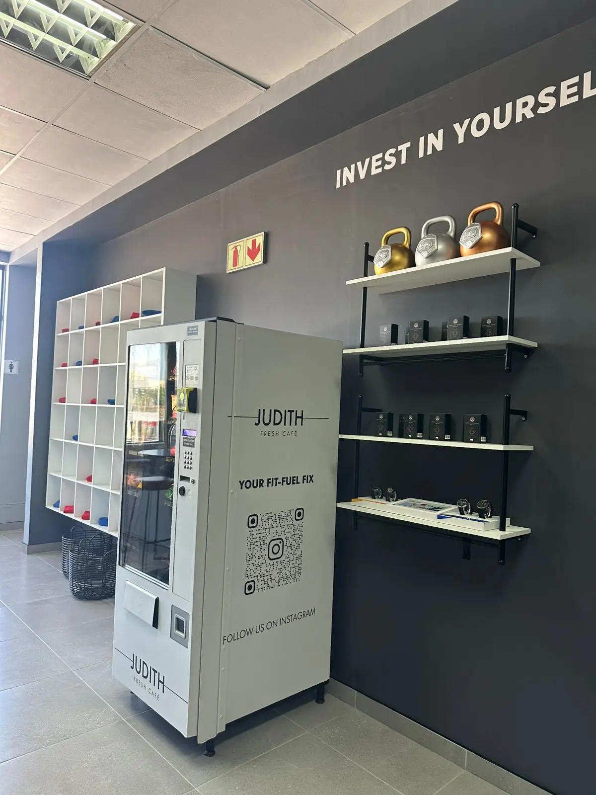 A white branded healthy-vending machine installed in a gym