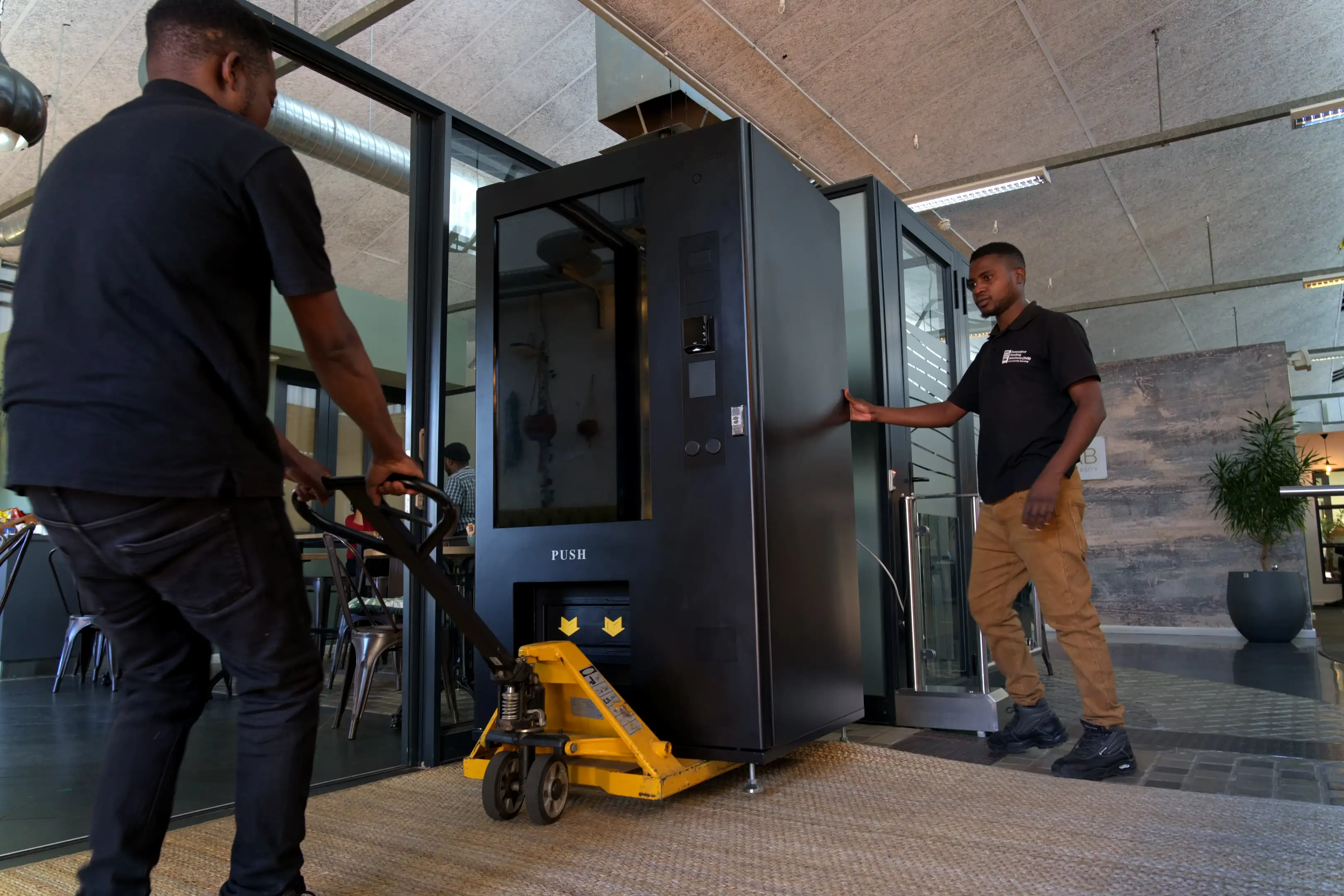 An IVS technician moving a vending machine into position with a pallet jack