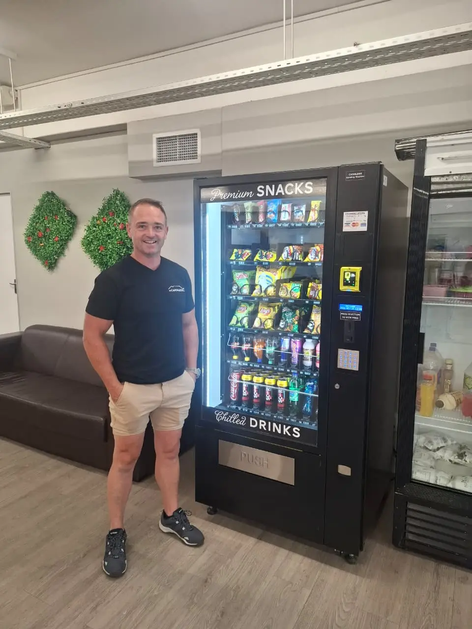 A client standing beside a newly installed CV1000 vending machine in an office