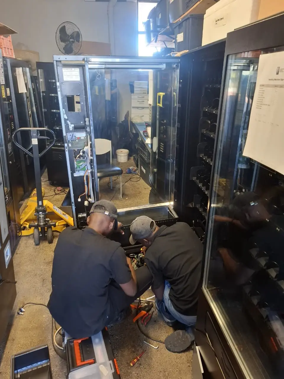 Two IVS technicians working inside an open vending machine