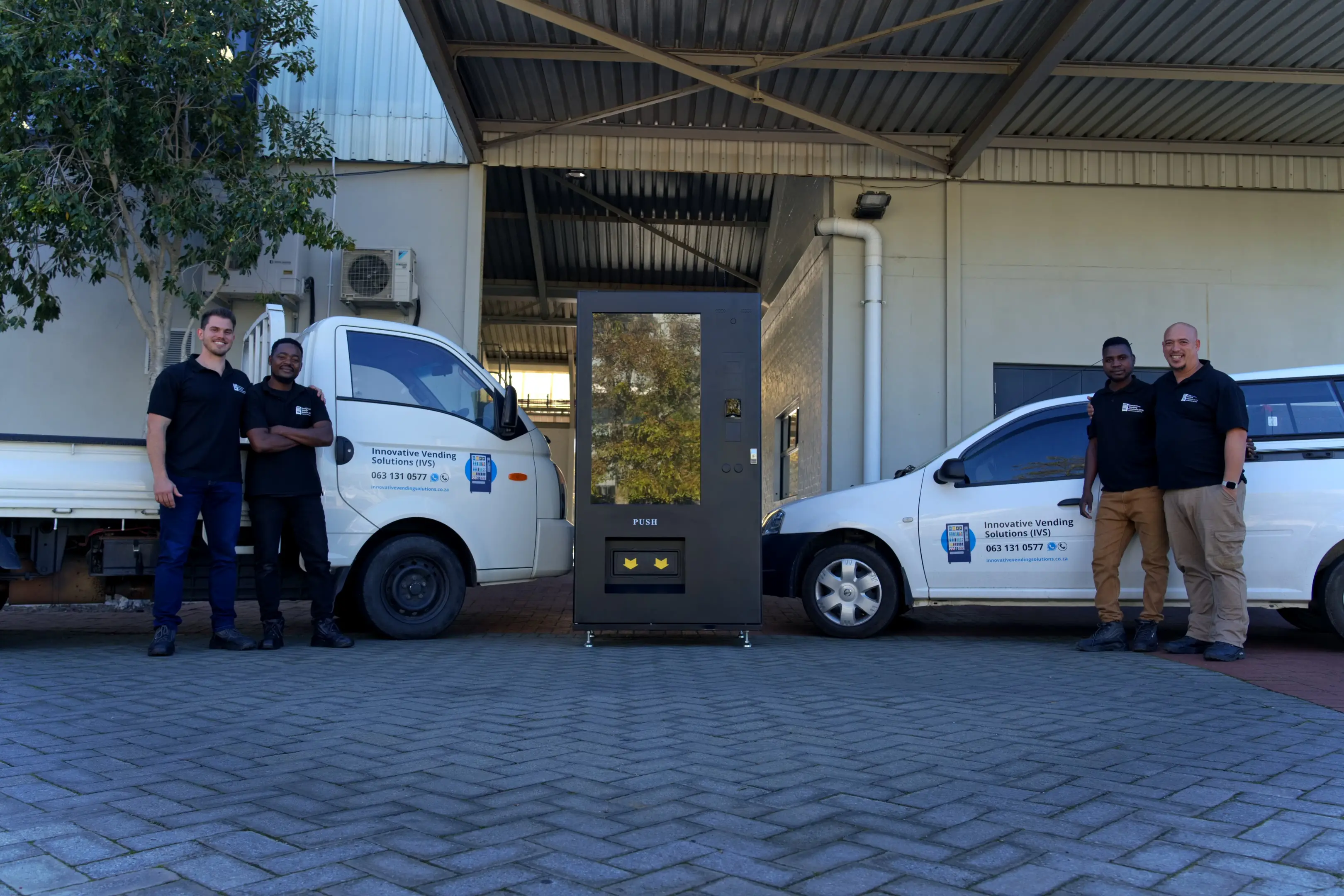 The IVS installation team with their branded vehicles and a vending machine